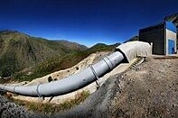 A massive pipe in the west coast mountain range leading to a highly elevated pump house