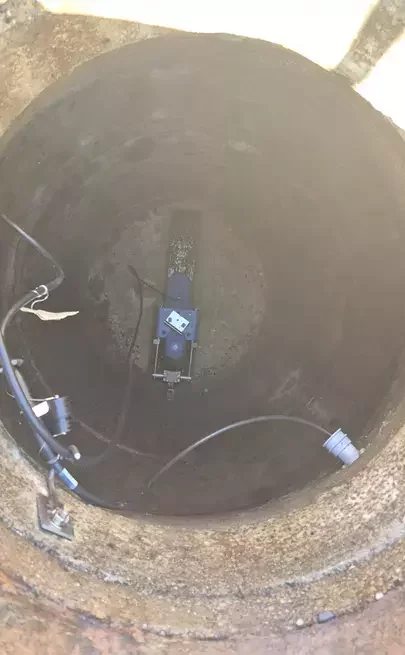 Overhead view into a metering manhole with a sewer flow meter  installed along the channel bottom.