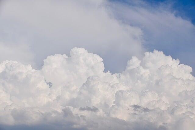 Bright white cumulus clouds against a blue sky with light haze.
